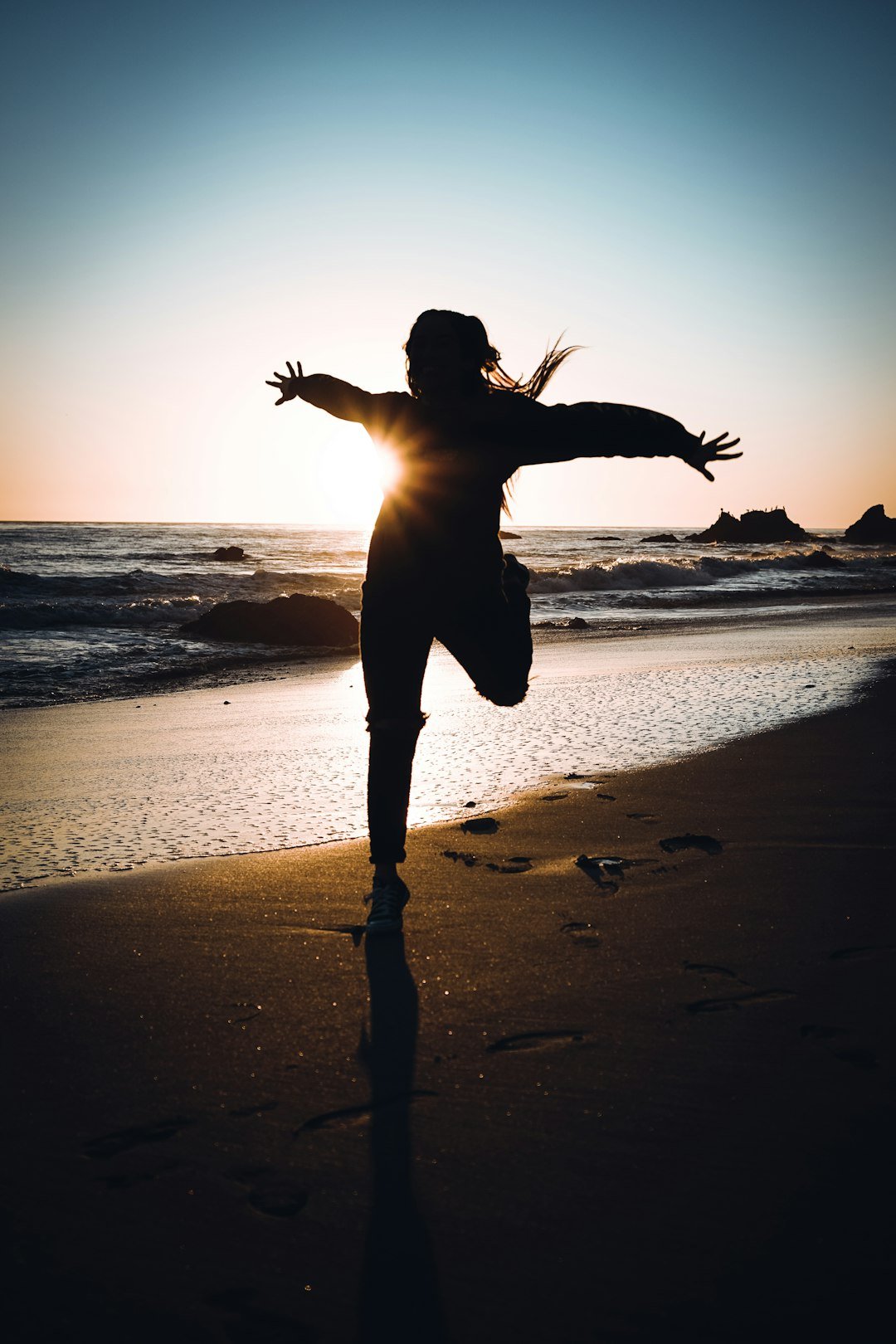 Photo by Jayy Torres silhouette of woman standing on beach during sunset
